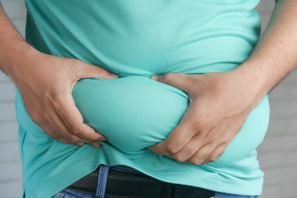 Person holding their belly, one of many common bloating causes explained by a dietitian