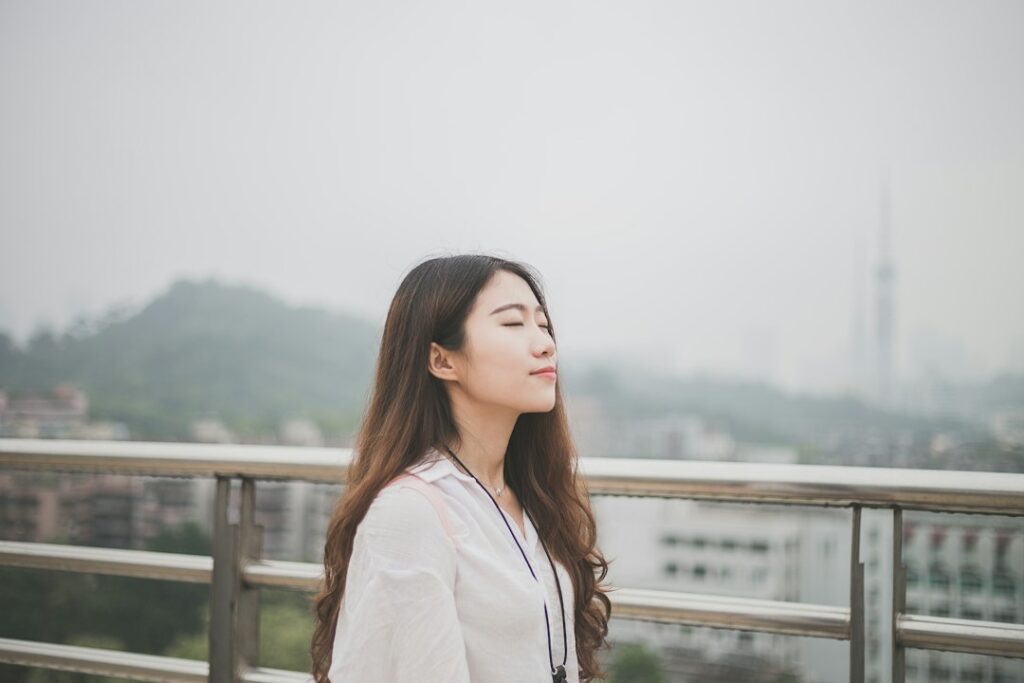 Woman with eyes closed taking a slow breath to calm IBS and anxiety