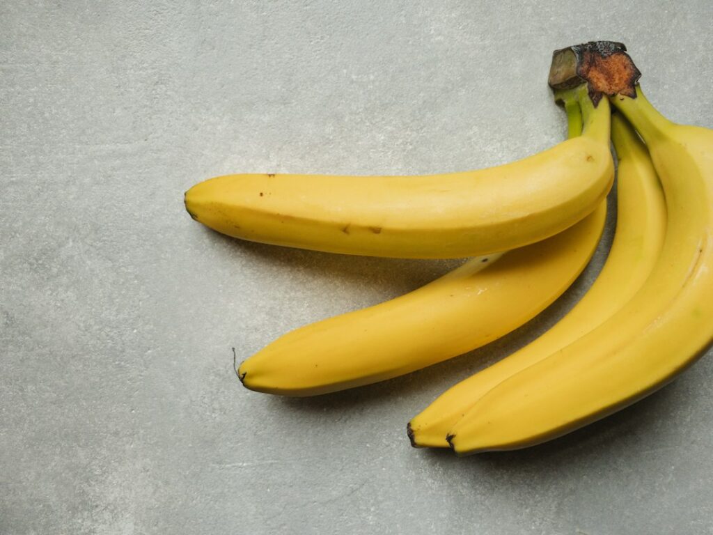 Yellow bananas on a table, firm bananas are low FODMAP for IBS (is banana low FODMAP)