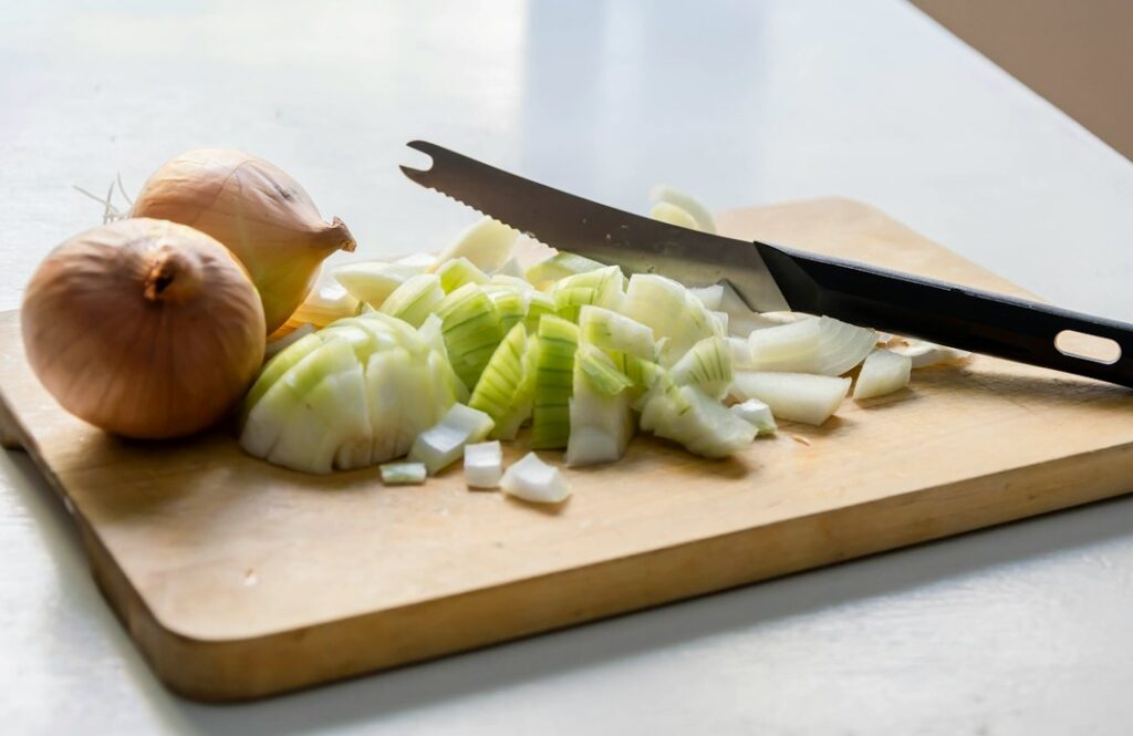 Chopped onions on a cutting board, a high FODMAP food for people with IBS (is onion low FODMAP)